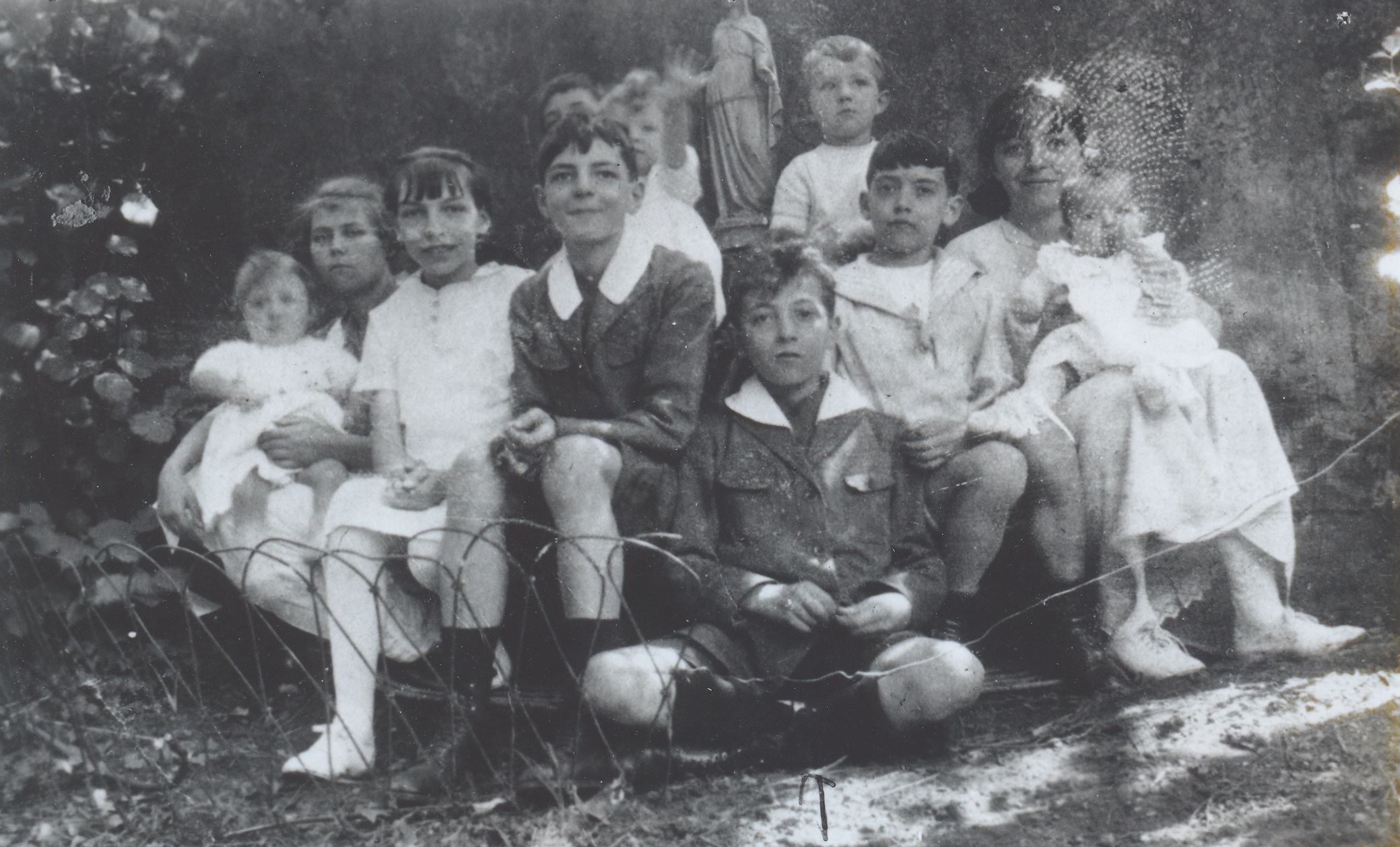 Henri Grouès avec ses frères (Léon, Daniel), sœurs (Elisabeth, Noëlle, Anne-Marie) et cousins (Jacques, Joujou et Henri Perra), devant la statue de la Vierge à Irigny, 1922. ©Emmaüs International